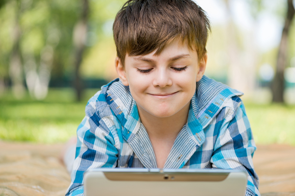 boy-using-tablet-PC-in-park