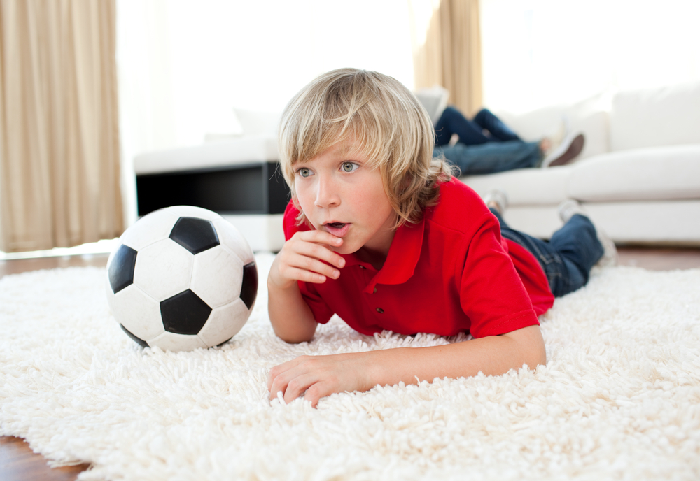boy-watching-football-match-lying-on-the-floor-in-the-living-room