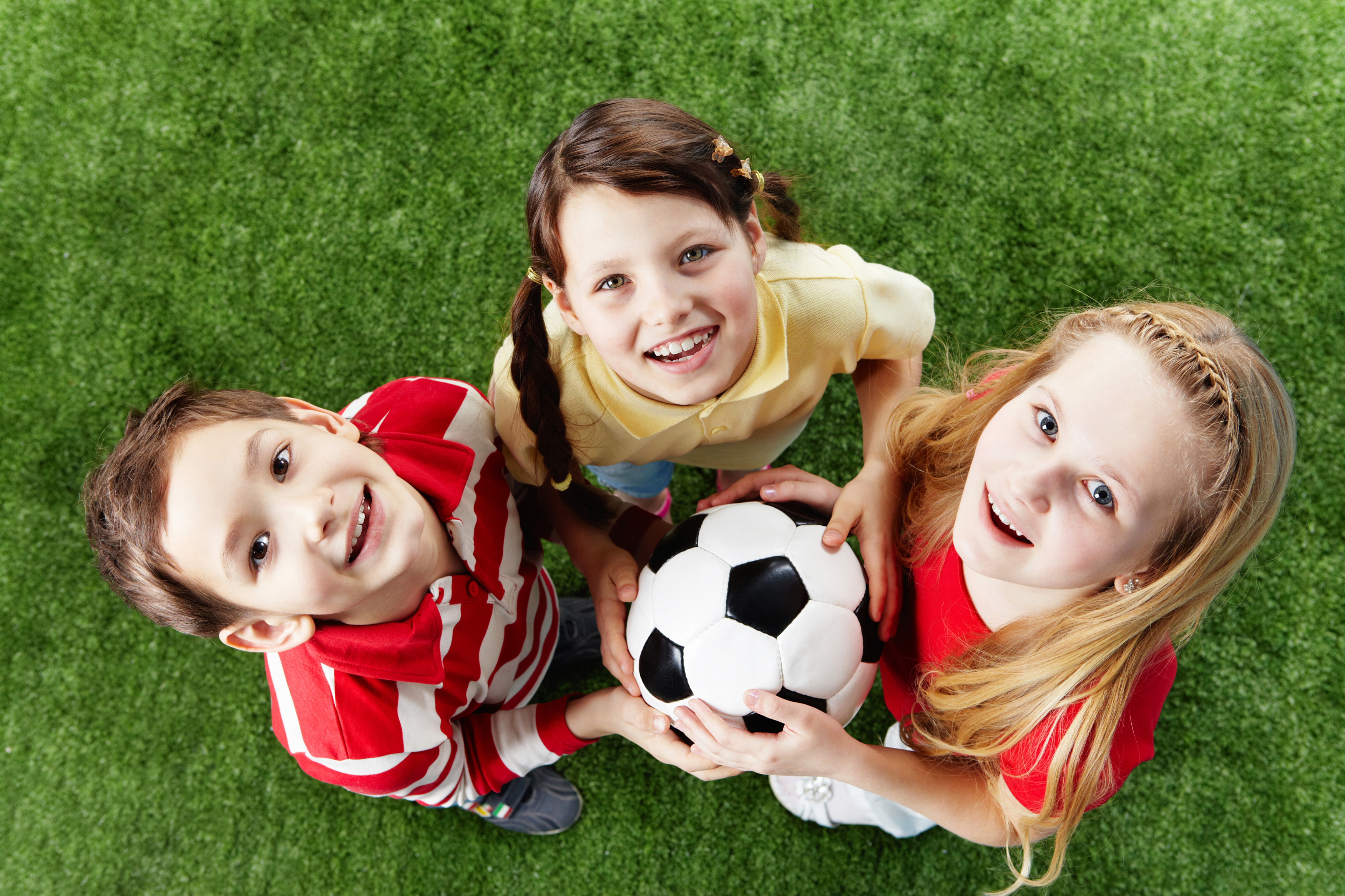 happy-friends-on-the-grass-with-ball-looking-at-camera