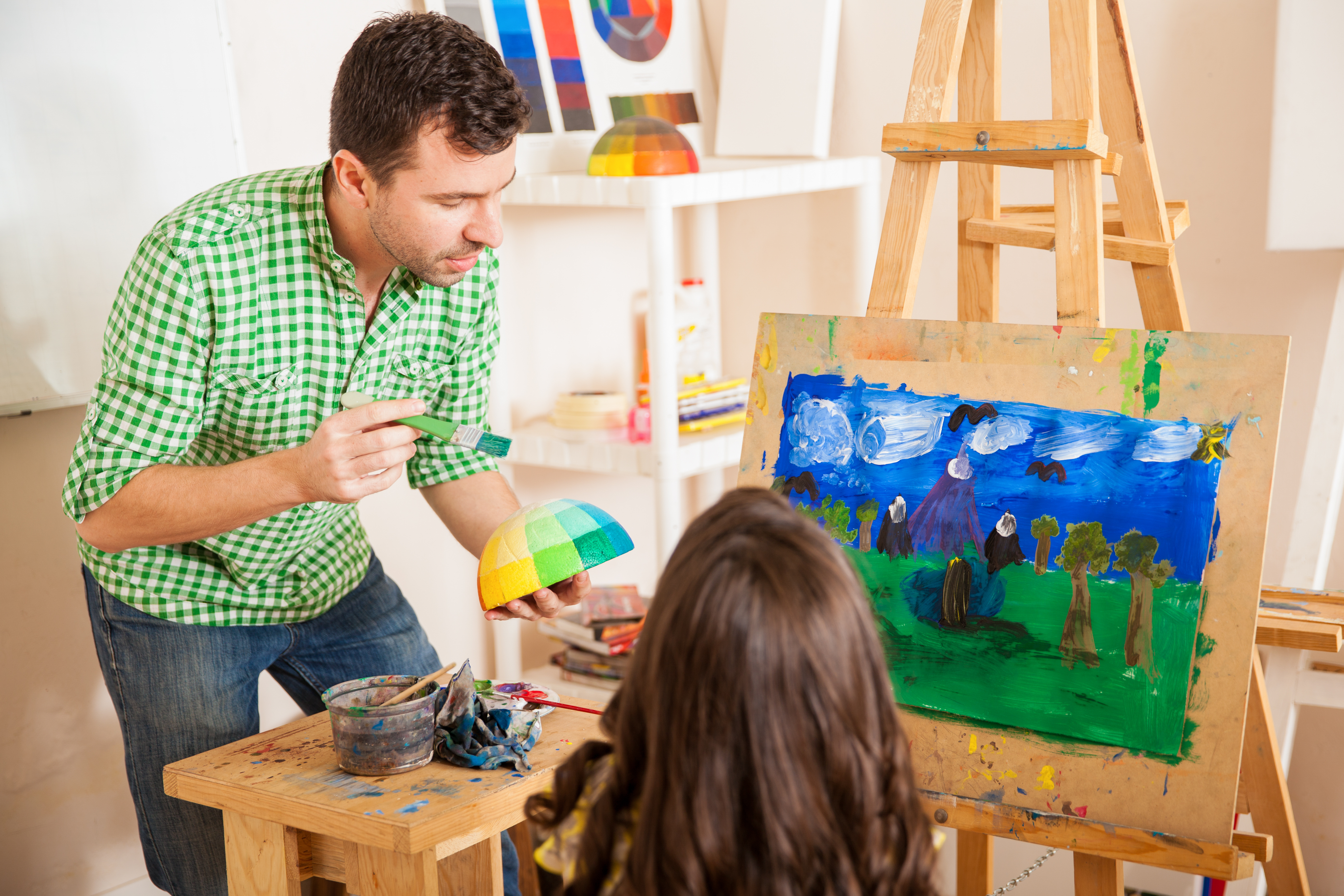 young-art-teacher-talking-about-colors-with-a-little-girl-during-class