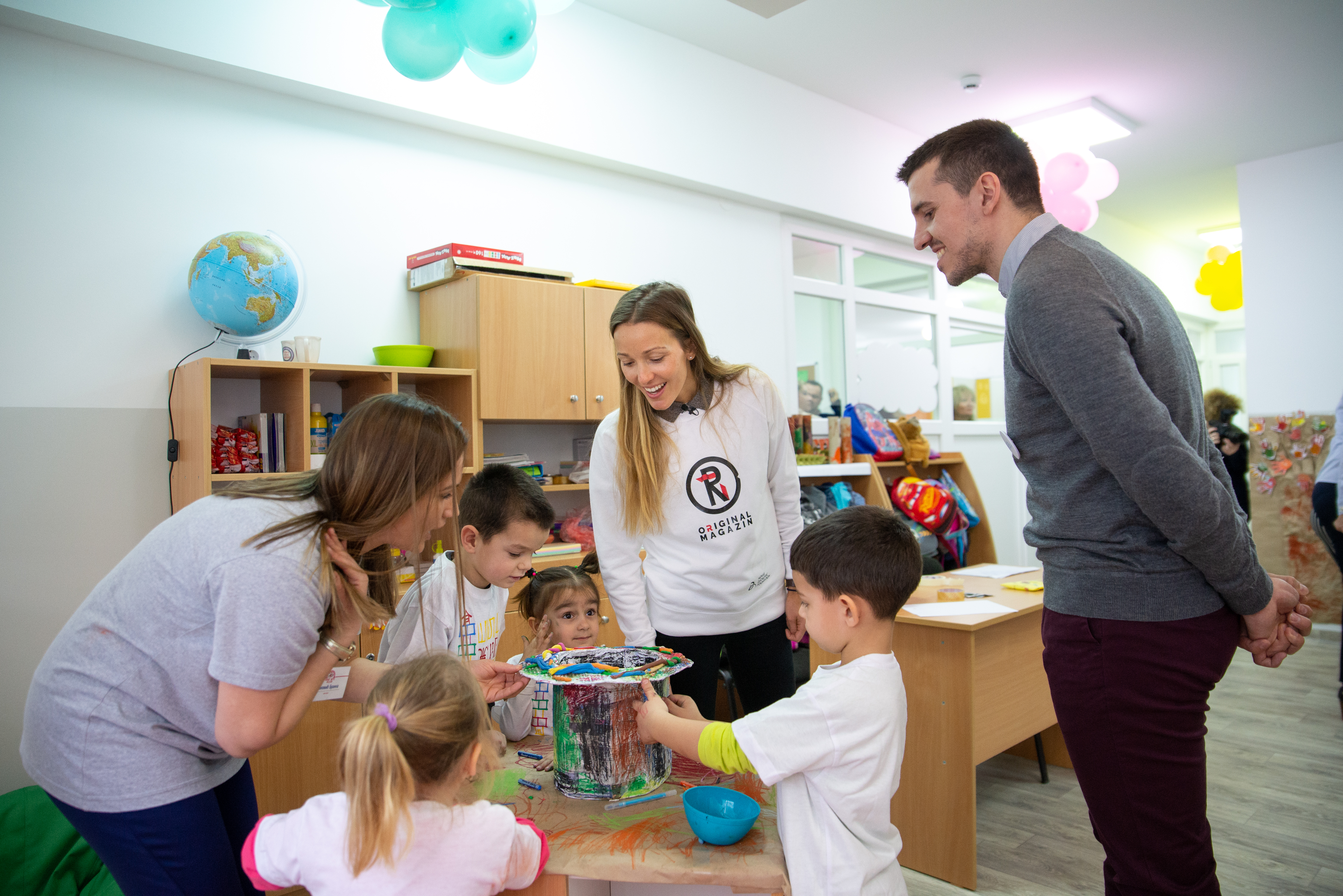 Branka, the teacher (left), Jelena Djokovic (center) and Marko Kovacevic (right) playing with kids during the opening of the kindergarten. 